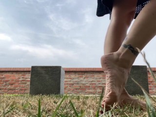 Slow motion milf barefoot in grass, wrinkled soles and red toes