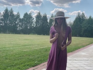 Sexy lady strolls with bare breasts in the park. Public