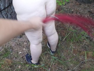 Naughty BBW spanked in the forest - amateur outdoor BDSM with flogger