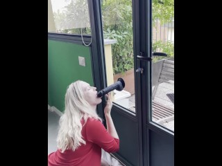 Horny blonde with big tits sucks a suction cup dildo in front of the window