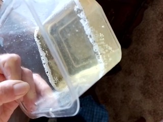 Close up sexy guy pissing in a plastic container
