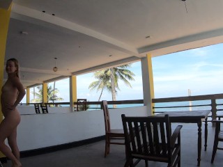 Naked girl walks on the balcony overlooking the ocean