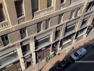 A woman undresses on a balcony in the city center. Public flashing.