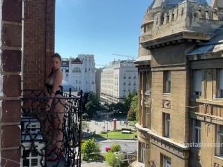 A woman undresses on a balcony in the city center. Public flashing.