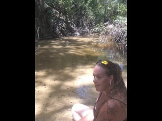 Cute long hair girl on her knees looking for shells to collect in popular spring creek