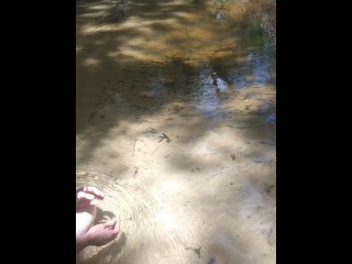 Cute long hair girl on her knees looking for shells to collect in popular spring creek
