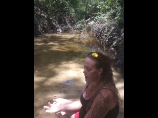 Cute long hair girl on her knees looking for shells to collect in popular spring creek