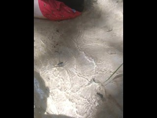 Cute long hair girl on her knees looking for shells to collect in popular spring creek