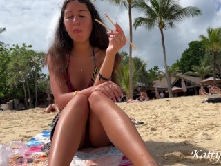 Девушка ест суши без трусиков среди людей на публичном пляже