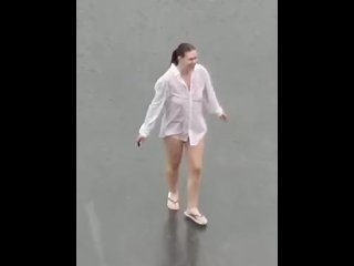 Dancing in the rain with wet white shirt on a busy parking loot