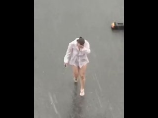 Dancing in the rain with wet white shirt on a busy parking loot