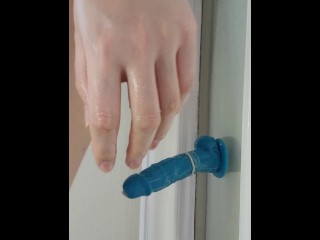 exhibitionist fucking a dildo against glass part of door
