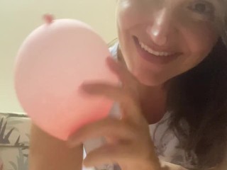 Woman plays with small pink balloon (the balloon doesn't burst)