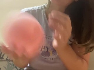 Woman plays with small pink balloon (the balloon doesn't burst)