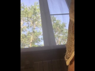 Girl sits on the window and inserts a tampon into her pussy during her period