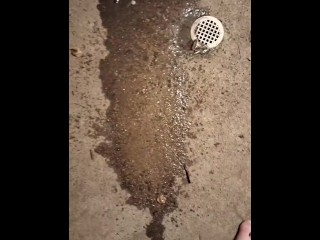 Pissing by a drain on the sidewalk