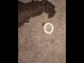 Pissing by a drain on the sidewalk