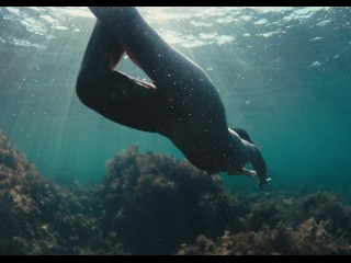 A naked buttty girl swims in the ocean, but someone is watching her