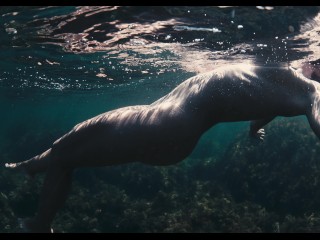 A naked buttty girl swims in the ocean, but someone is watching her