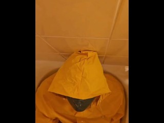 Pissing over  yellow rainwear with yellow gloves and latex mask