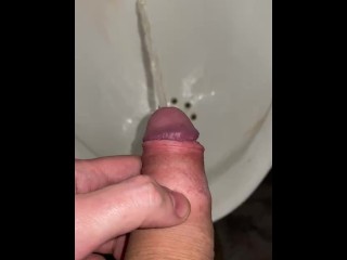 Pissing in a urinal close up in a public toilet