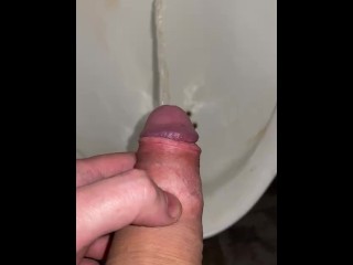 Pissing in a urinal close up in a public toilet