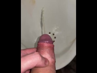 Pissing in a urinal close up in a public toilet