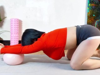 How a girl in orange clothes uses a small yoga ball to show off her figure