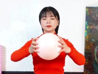 The big-breasted beauty in orange top performs fitness exercises with a small yoga ball