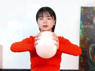 The big-breasted beauty in orange top performs fitness exercises with a small yoga ball